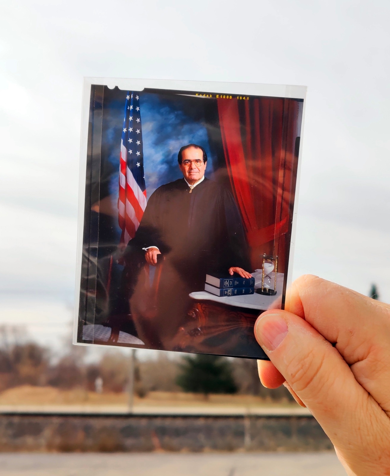 A hand holding the original color transparency from David DeJonge's portrait of Justice Antonin Scalia